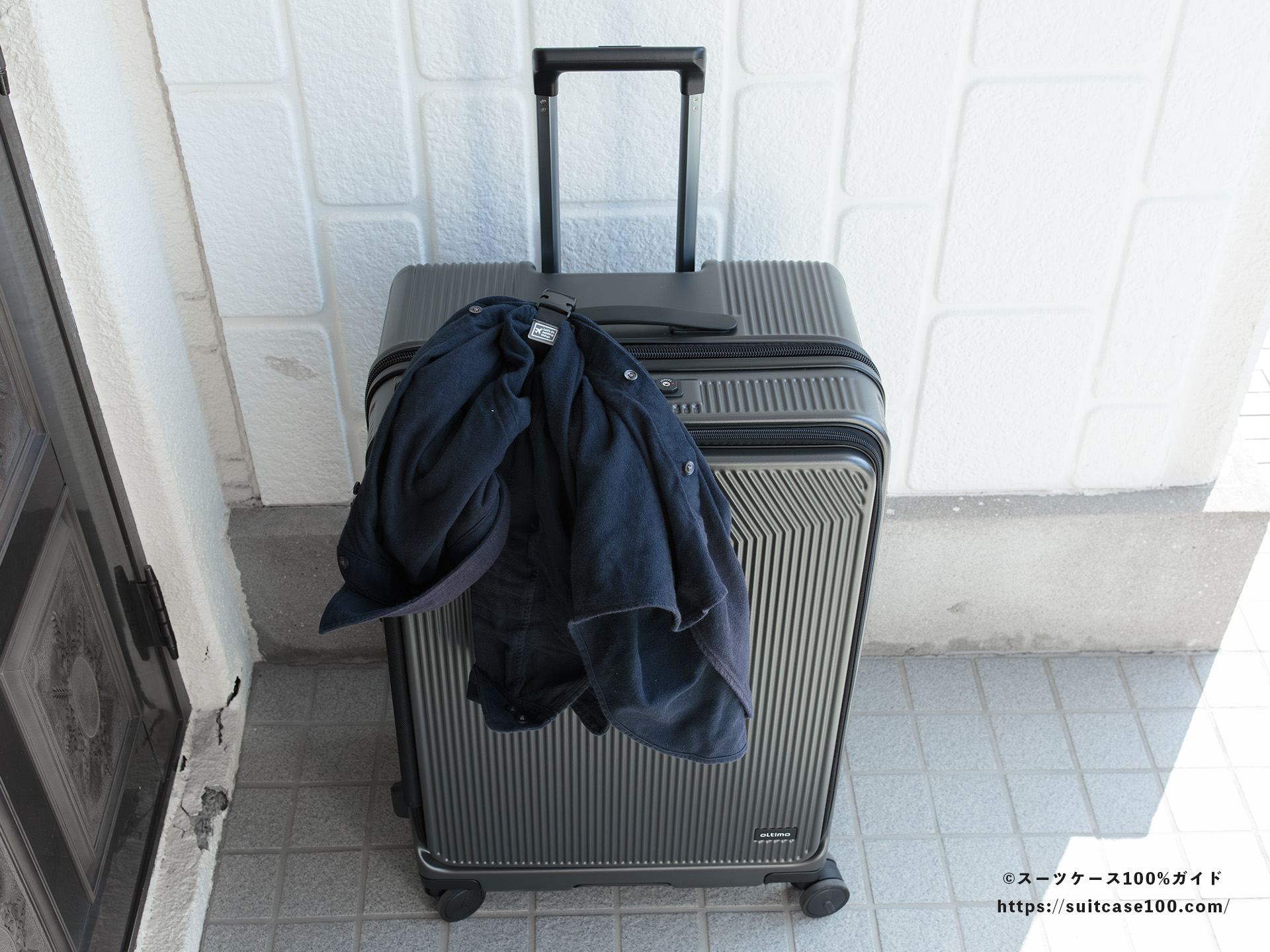ダイソー スーツケースと手荷物まとめベルト レビュー Lサイズのスーツケースに装着してシャツをかけた図