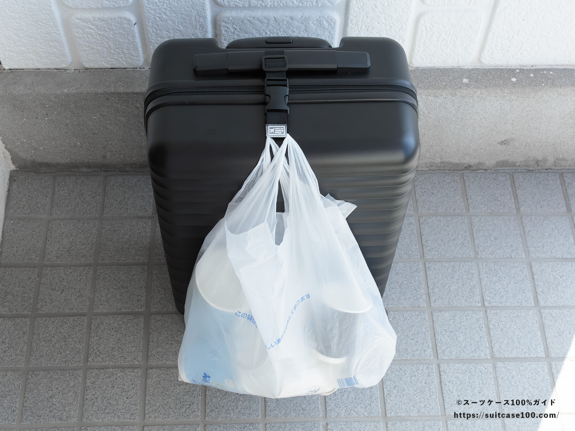 ダイソー スーツケースと手荷物まとめベルト レビュー Sサイズのスーツケースに装着してレジ袋をかけた図 正面