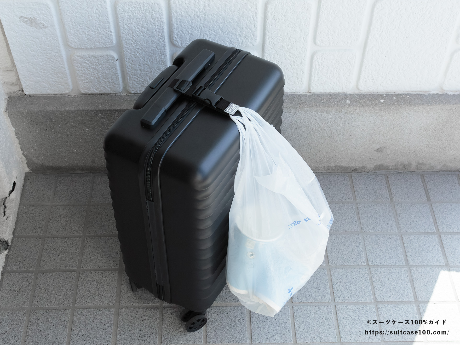 ダイソー スーツケースと手荷物まとめベルト レビュー Sサイズのスーツケースに装着してレジ袋をかけた図 斜め上