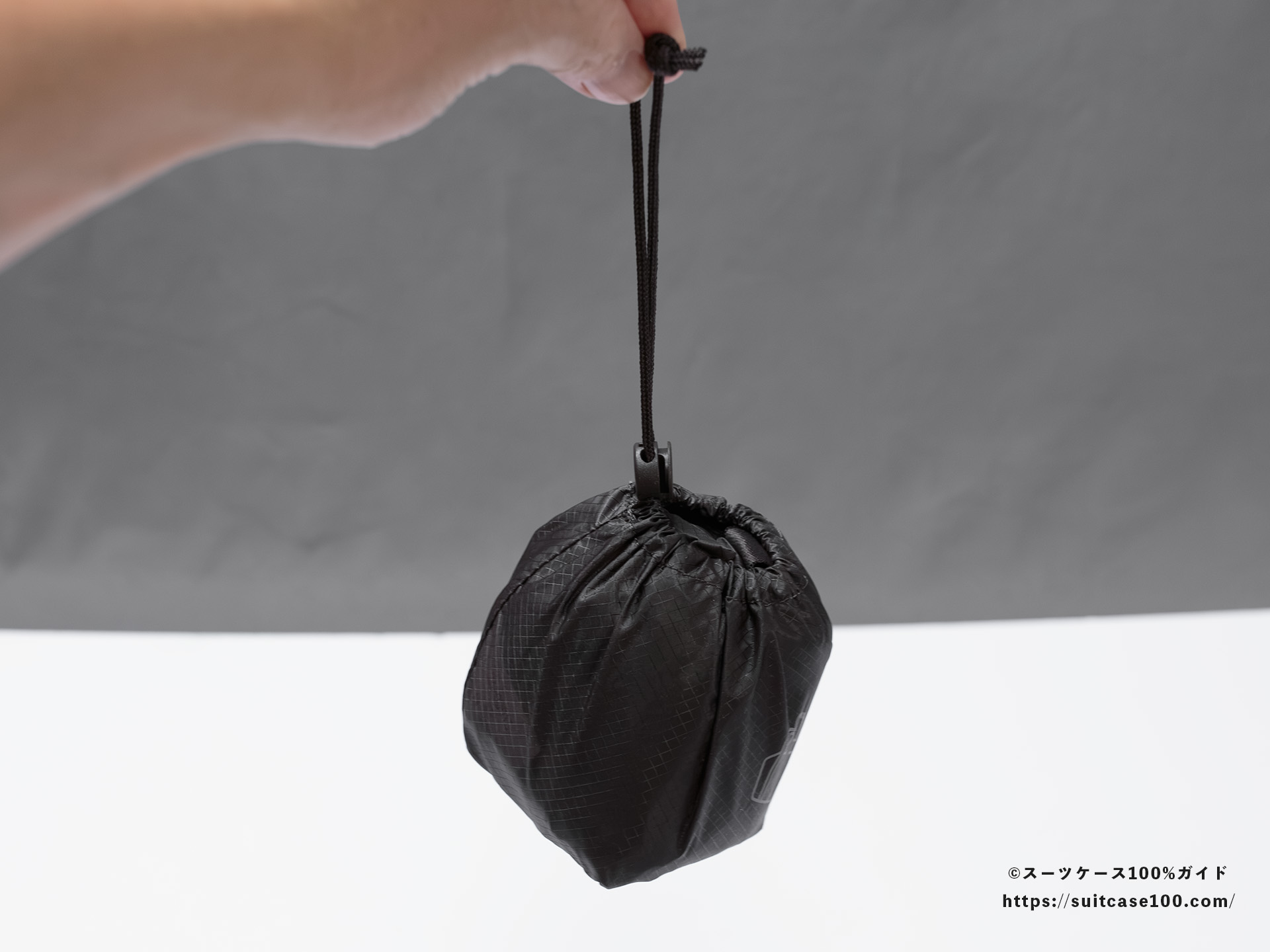無印良品 軽量ナイロン小さくたためるボストンバッグ 外観レビュー 収納状で紐を持っている図
